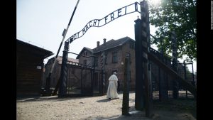 The Catholic Christian pope, Francis I, enters the front gate of the former Nazi death camp in Auschwitz, Poland. The sign above the gate says, "work sets you free".