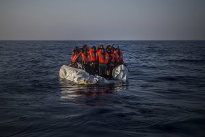 Fleeing from Libya, the refugees sit in the middle of the Mediterranean Sea hoping for rescue.