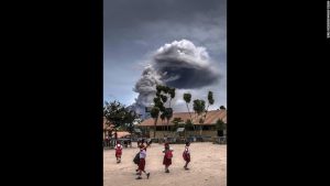 School children play while the ominous and threatening Mount Sinabung volcano looks poised to erupt.