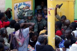 People in haiti rush soldiers at a food depot as the island continues to recover from the devastation of Hurricane Matthew.