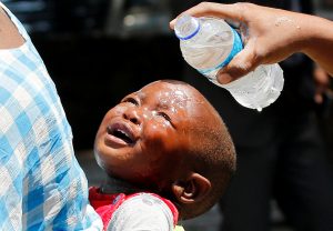 A baby is dowsed with water after being tear gassed by police during a riot between police and street vendors in Zimbabwe.